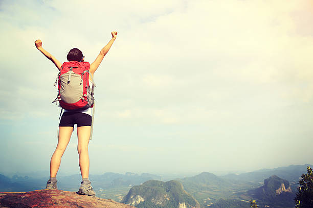 istock cheering woman hiker open arms at mountain peak 472236968