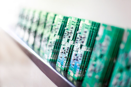 Large group of stacked green silicone microchips in a row in a production line. Selective focus, no people.