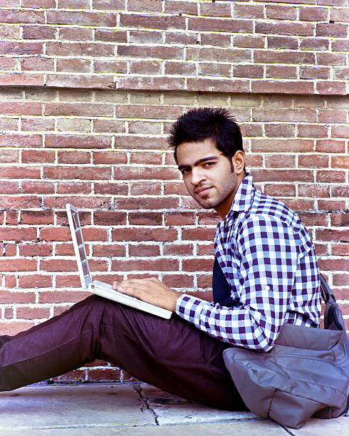 istock Indian college student using his laptop computer in the campus. 472237365