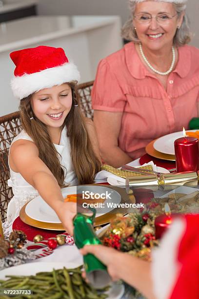 Geschwister Ziehen Christmas Cracker Mit Esstisch Stockfoto und mehr Bilder von 12-13 Jahre - 12-13 Jahre, Alter Erwachsener, Cracker