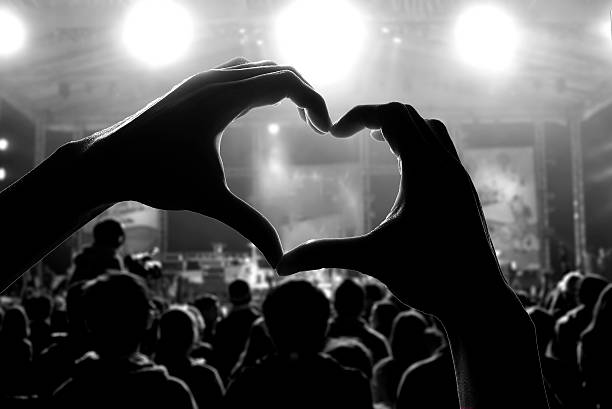 Silhouette of hands making a heart at a concert crowd of people at during a concert with a heart shaped hand shadow hand fan photos stock pictures, royalty-free photos & images