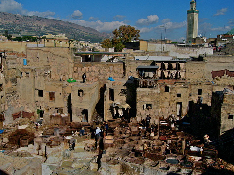 Fes,Morocco-November 24,2008:Men working in the leather tanneries of Fes in foul smelling conditions. In colored reservoirs they are soaking the hides to give them the exact color.