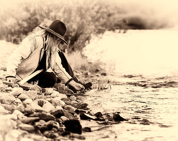 istock Western prospector picks up pebbles from river bed 472241481