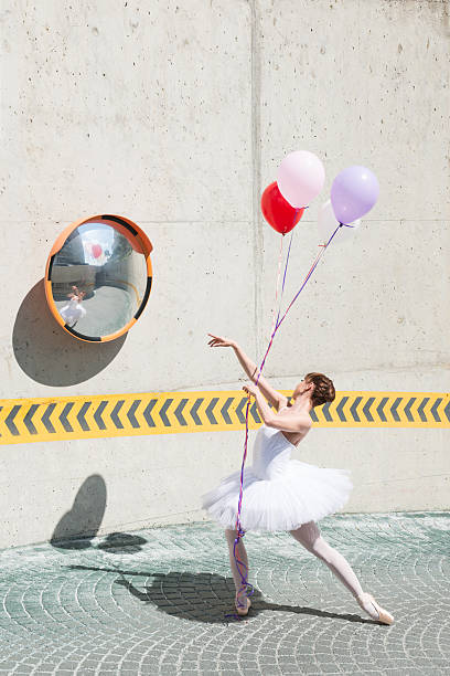 istock Beautiful ballet dancer is posing front of concrete with balloons 472257386
