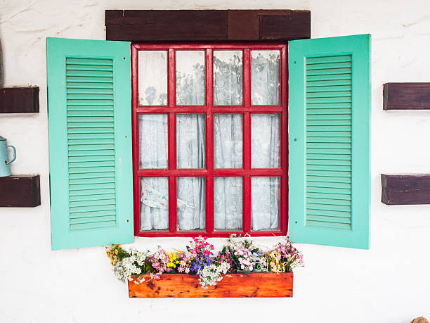 istock opened wooden shutter window on white wall with flower bed 472258922