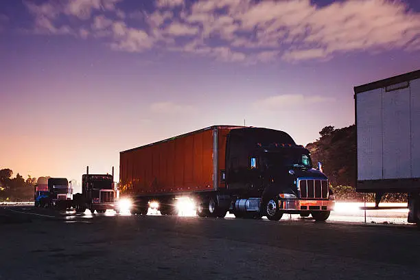 Photo of A line of big rig trucks during sun rise