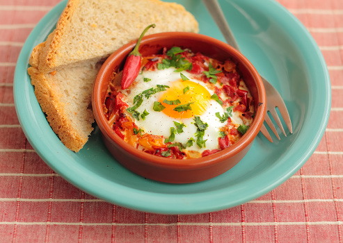 Eggs poached in tomato sauce and other vegetables served with bread.