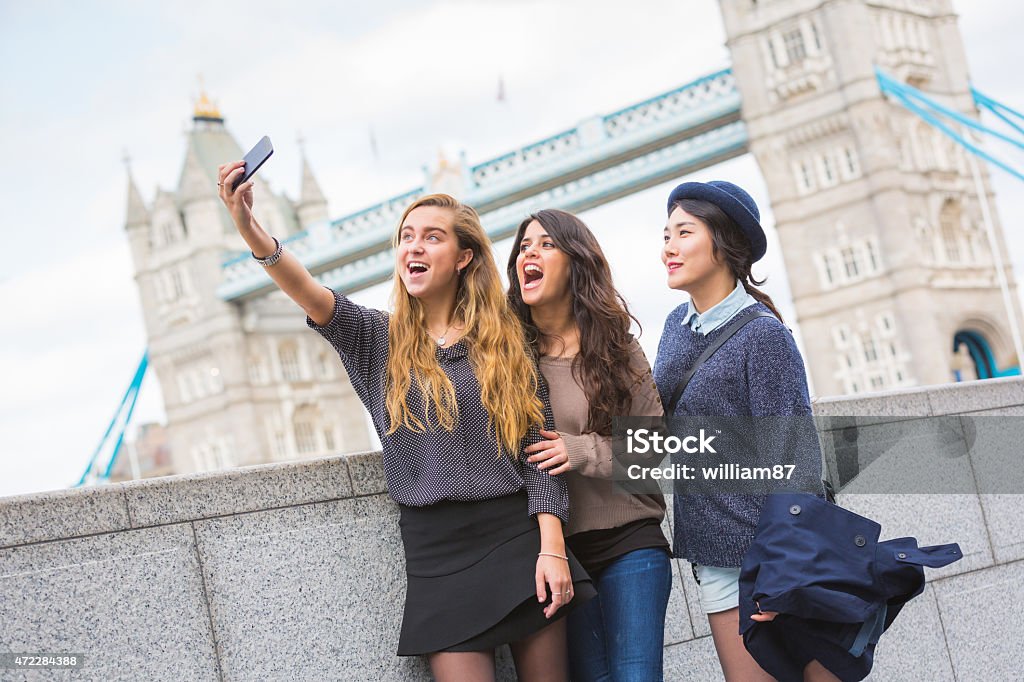 Multiracial group of girls taking a selfie in London Multiracial group of girls taking a selfie in London with Tower Bridge on background. The group consists of three girls, one is from Korea, one from Spain and one from Holland London - England Stock Photo