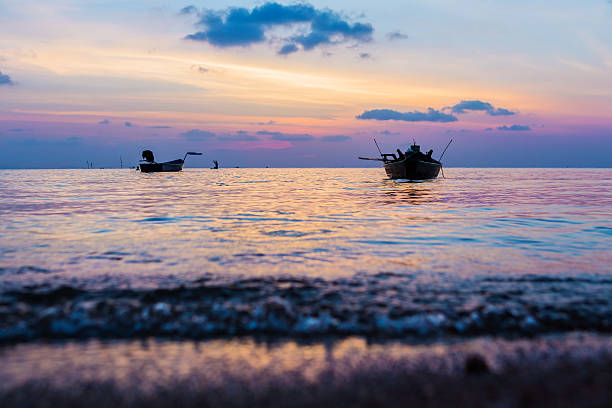 Seething wave of calm beautiful sunset with fishing boats on the island paradise of Koh Phangan in Thailand. 