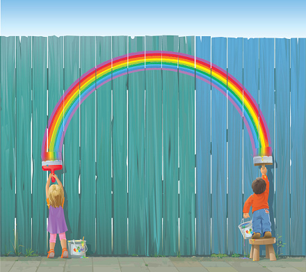 A boy and a girl paint a rainbow on a fence. 