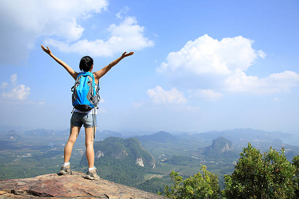 istock cheering woman hiker open arms at mountain peak 472290570