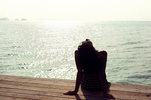 istock Young pretty woman sitting alone on the pier 472302140