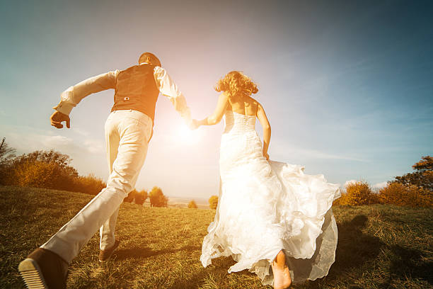 istock Newly married couple running up a hill 472305012