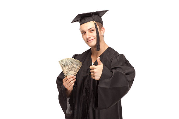 studenten in graduierung kleid mit geld und zeigen daumen hoch - twenty dollar bill fanned out currency dollar sign stock-fotos und bilder