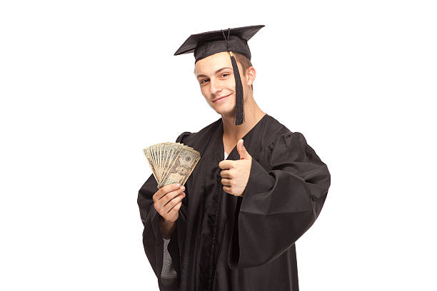 Student in graduation gown with money and showing thumbs up stock photo