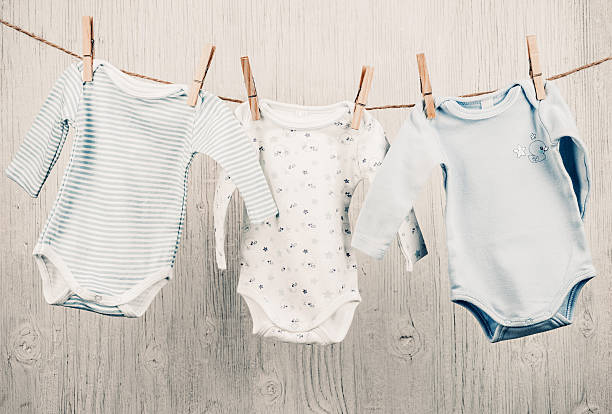 babykleidung auf der wäscheleine hängen. - babybekleidung stock-fotos und bilder