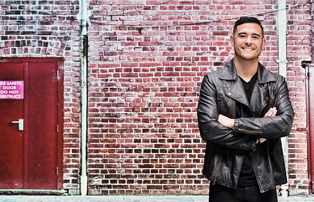 istock Smiling man in front of brick wall 472311896