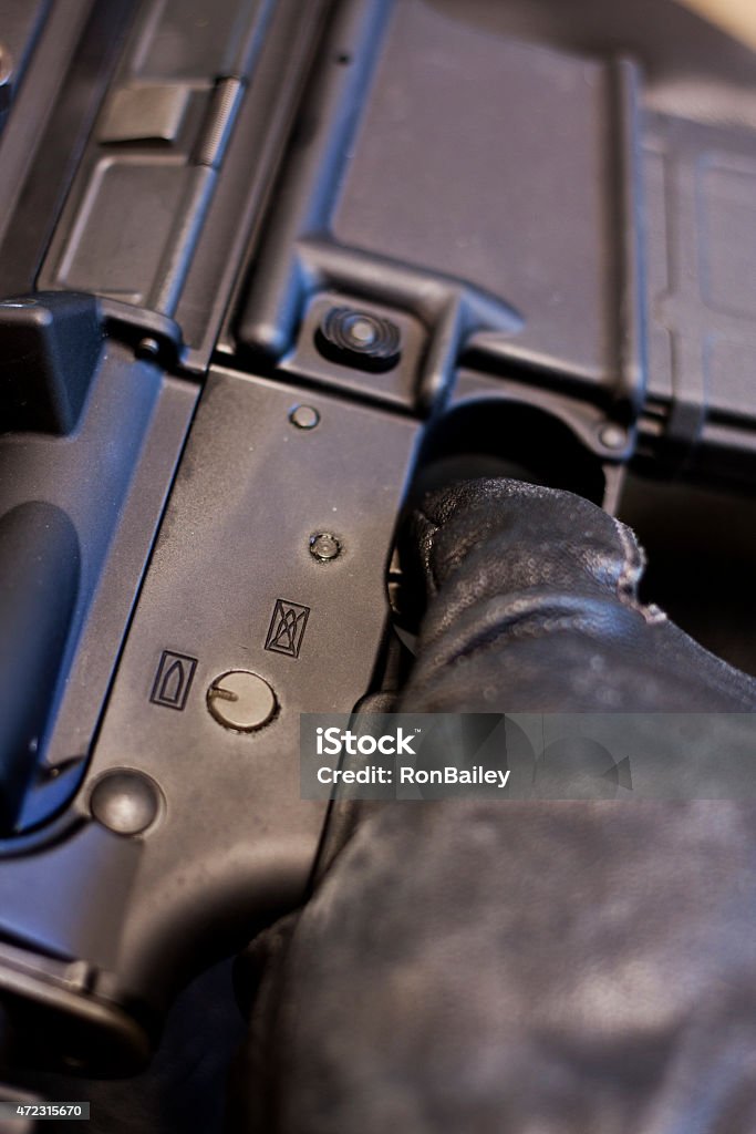 AR15 Black Gloves - Finger On Trigger A semi-automatic AR-15 "assault rifle" held by a hand wearing black leather gloves with the trigger finger on the trigger, ready to fire. 2015 Stock Photo