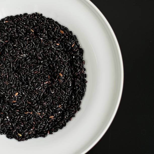 black rice heap in ceramic dish top view surface close up isolated on black background