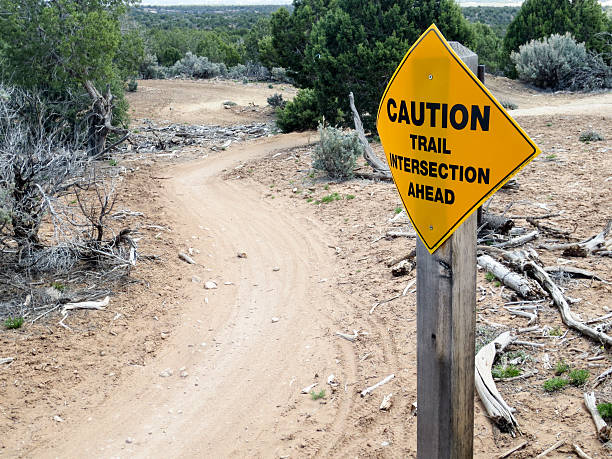 istock Caution trail intersection ahead sign with curving dirt trail 472323206