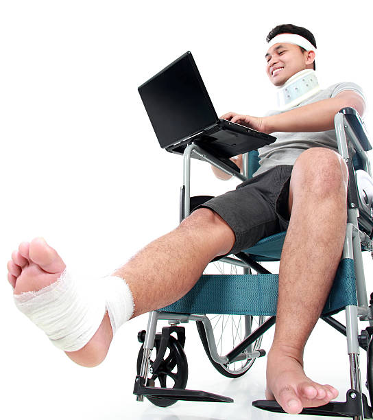 junger mann im rollstuhl mit laptop arbeiten - accident occupation working physical impairment stock-fotos und bilder