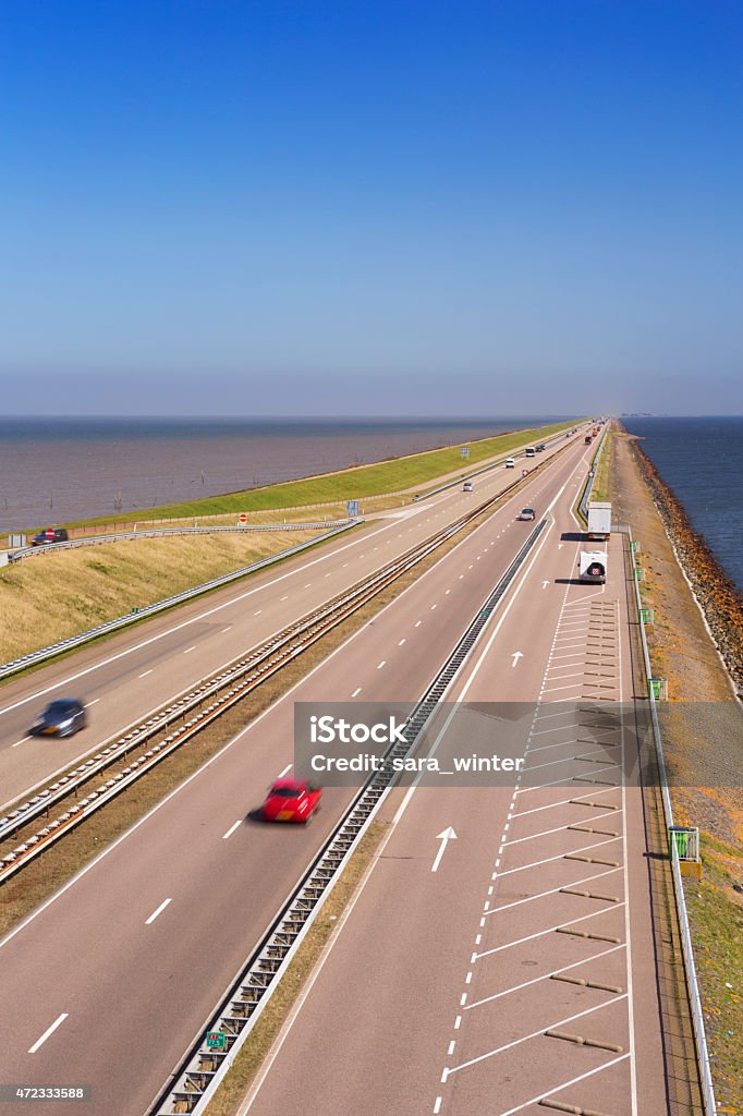The 'Afsluitdijk' dike damming off the former Zuiderzee, The Netherlands Traffic on the Afsluitdijk on a sunny day in The Netherlands. The Afsluitdijk is a dike over 32km damming off the former Zuiderzee, a salt water inlet of the North Sea. 2015 Stock Photo