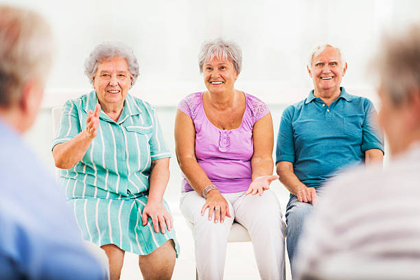 istock Smiling seniors sitting in nursing home and communicating . 472336720