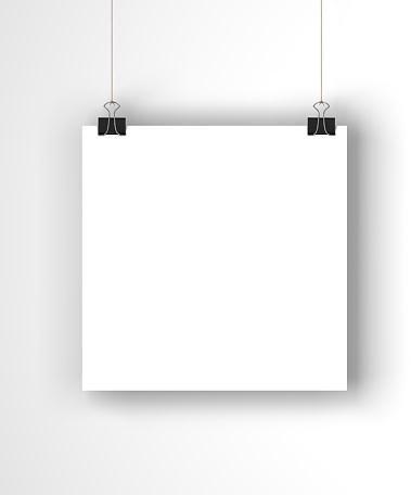 A blank white square poster is suspended against a plain white wall. The paper is being held by a paper clip which is hanging on a piece of string. Light is coming from the left of the image which casts a soft shadow onto the background. The paper is ready for you to add your own designs and artwork.