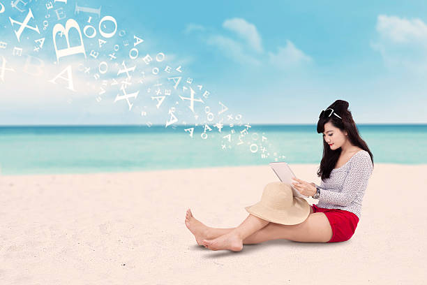 jeune femme utilise sa tablette au bord de mer - digital tablet beach pc reading photos et images de collection