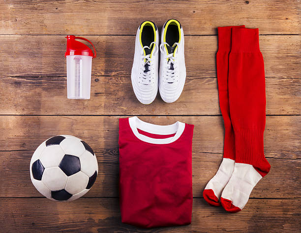 Football gear lying organized on a wooden floor Various football stuff lined up on a wooden floor background football socks stock pictures, royalty-free photos & images