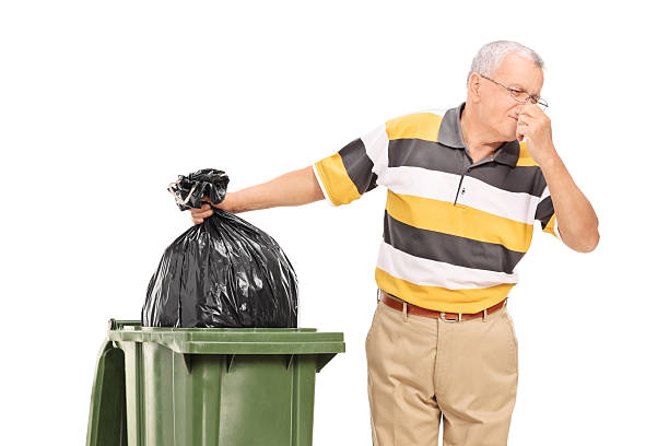 istock Senior throwing away a stinky bag of trash 472343210