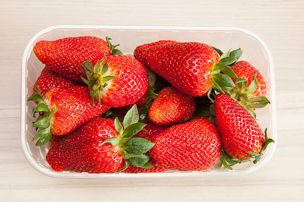 istock Strawberries in plastic bowl on wood 472345520