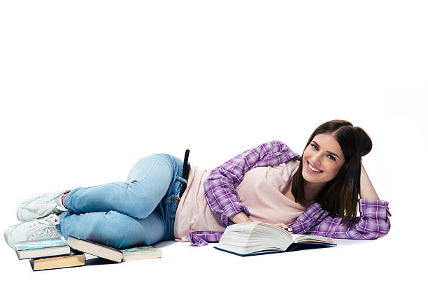 istock Smiling woman lying on the floor with book 472350408