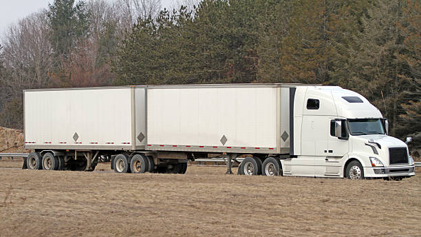 Two trucks in a parking lot with an empty container trailer open gates at the back, ready to load products, goods cargo