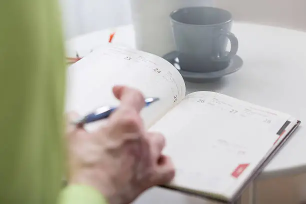 Close-up of busy woman holding weekly organiser