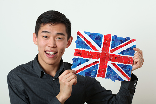 Young Asian student showing UK national flag and looking at camera