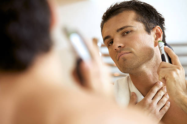 riflessione di giovane uomo in specchio da barba con rasoio elettrico - shaving men electric razor reflection foto e immagini stock