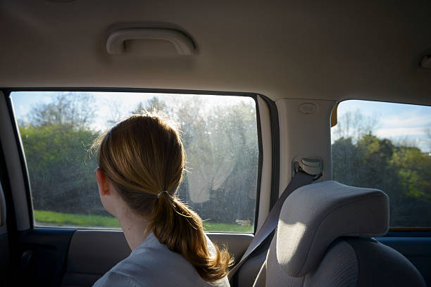 istock Young woman in backseat looking out window on highway 472366570