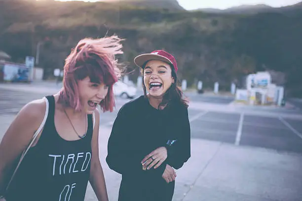 Photo of Grunge girls laughing together in a parking lot