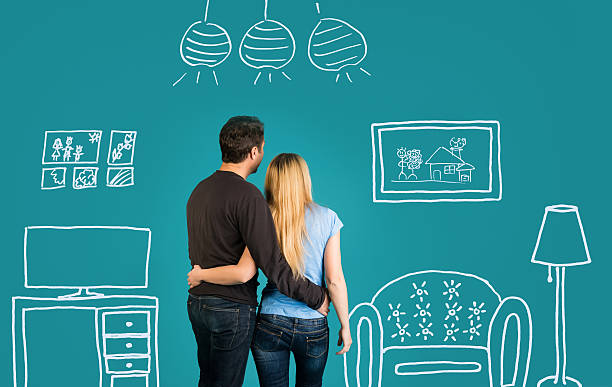 Family With Sketch Drawing Of Their Future Flat Interior. Back view Of Happy Couple Dreaming Of Their New Home And Furnishing On Blue Background. Family With Sketch Drawing Of Their Future Flat Interior. family photo on wall stock pictures, royalty-free photos & images