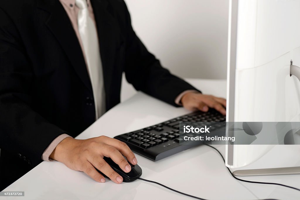 Business Man Typing Business man with suit typing with keyboard on white desk 2015 Stock Photo