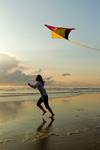 A woman flies a kite near sunset on the beach in Newport, Oregon.
