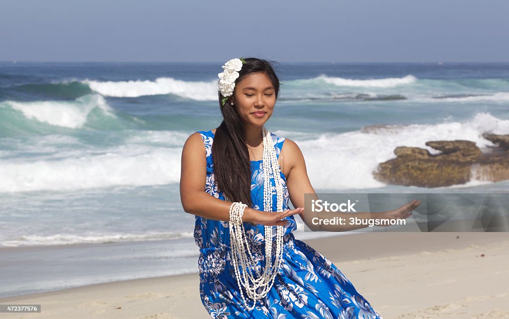 Beautiful Teenage Hula Dancer on an Empty Beach A beautiful teenage girl dancing hula in a traditional hula dress with her eyes closed. She is wearing a shell necklace and has a plumeria flower in her hair.  The beach is empty and there is copy space Hula Dancer Stock Photo