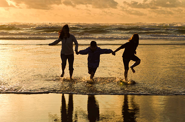 Rodzina działa na plaży o zachodzie słońca. – zdjęcie