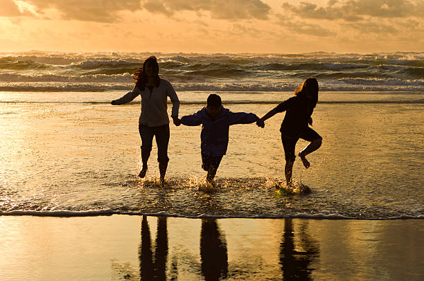 As corridas em família no surf ao pôr do sol. - foto de acervo