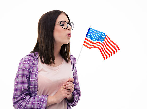 istock Young cute woman blowing US flag 472386316