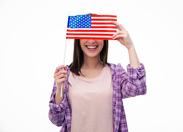 istock Smiling young student covering her eyes with flag 472386378