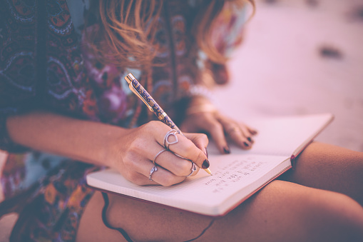 Boho girl writing in her diary wearing a floral dress