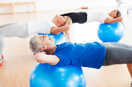 People exercising in gym,using pilates ball