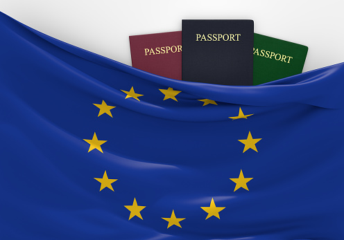 European Union flag and three passports in different colors, representing freedom of travel to and from the EU countries.